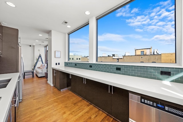 kitchen with light wood finished floors, tasteful backsplash, recessed lighting, stainless steel appliances, and light countertops