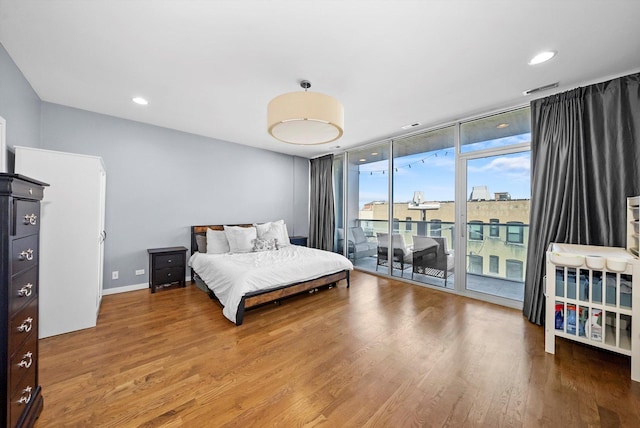 bedroom with visible vents, wood finished floors, floor to ceiling windows, recessed lighting, and access to exterior