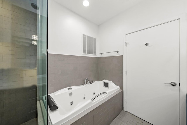 bathroom featuring visible vents, a shower stall, tile walls, and a tub with jets