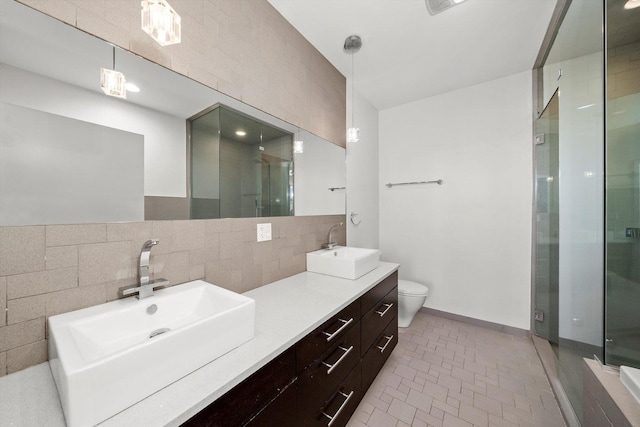 bathroom featuring a sink, toilet, a stall shower, and double vanity