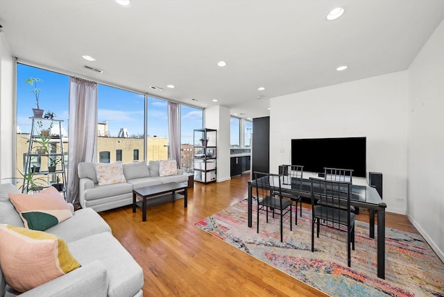 living area featuring visible vents, baseboards, a wall of windows, recessed lighting, and wood finished floors