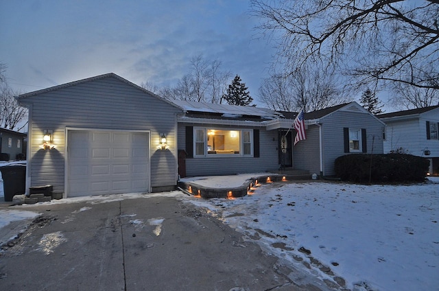 ranch-style home featuring roof mounted solar panels, driveway, and an attached garage