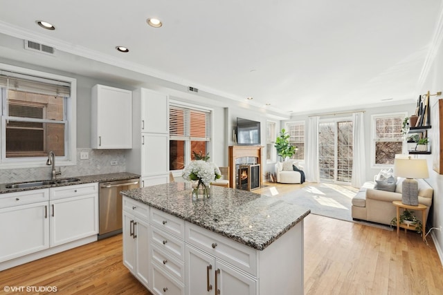 kitchen featuring a premium fireplace, white cabinetry, dishwasher, and sink