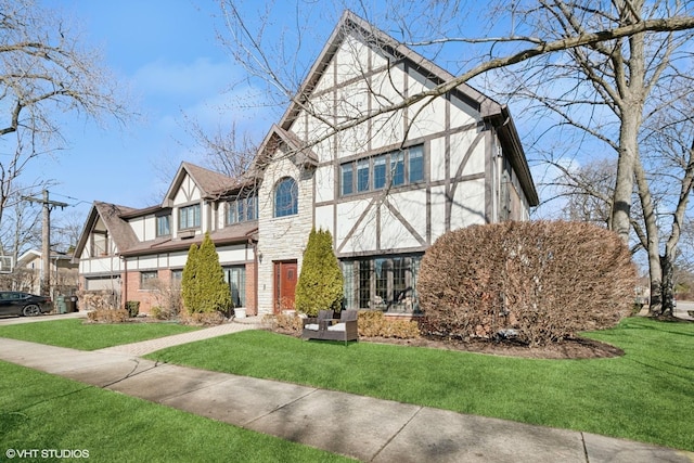 english style home featuring stone siding, stucco siding, and a front yard