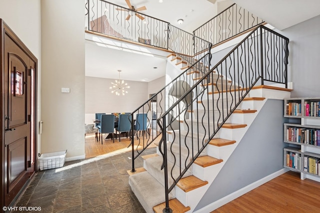 foyer entrance with a towering ceiling, dark wood-style floors, baseboards, and an inviting chandelier