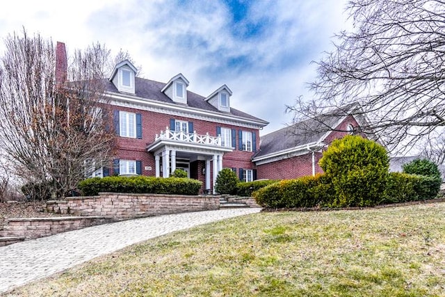 colonial house featuring brick siding and a front lawn