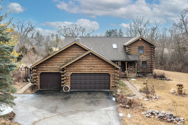 log cabin featuring aphalt driveway, covered porch, a garage, and log siding