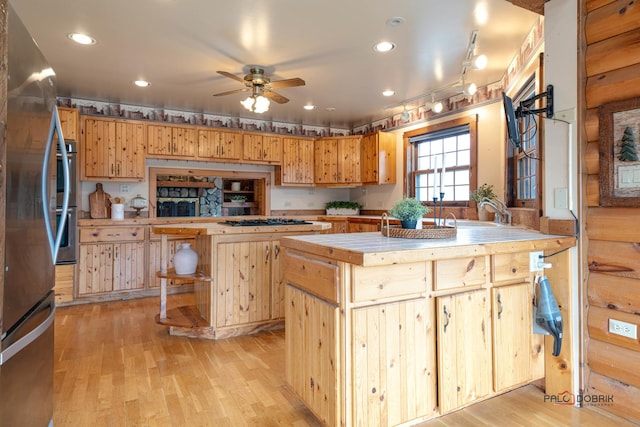 kitchen with ceiling fan, a center island, light wood-style floors, a sink, and recessed lighting