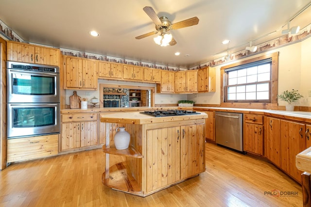 kitchen featuring stainless steel appliances, light countertops, a kitchen island, and light wood-style flooring