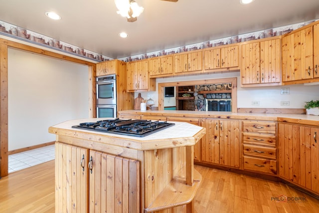 kitchen featuring light wood finished floors, tile countertops, double oven, gas cooktop, and recessed lighting