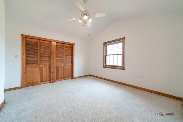 unfurnished bedroom featuring baseboards, a ceiling fan, light colored carpet, lofted ceiling, and a closet