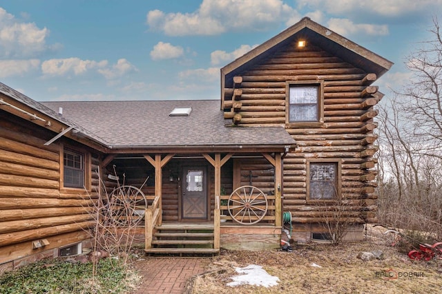 log cabin featuring a porch, a shingled roof, and log siding