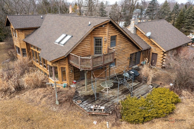 back of house with a deck, a shingled roof, a chimney, and log siding