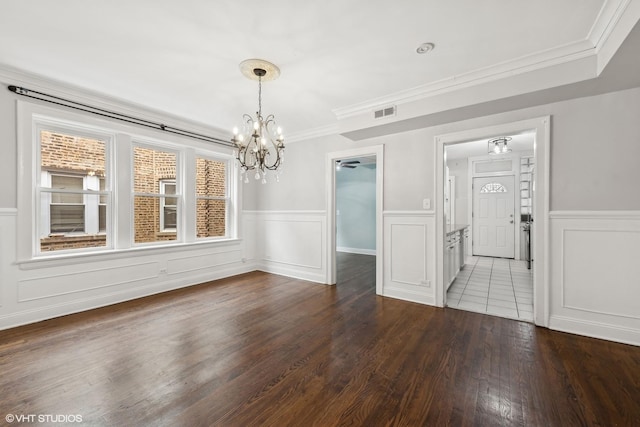 unfurnished dining area featuring wainscoting, visible vents, crown molding, and wood finished floors