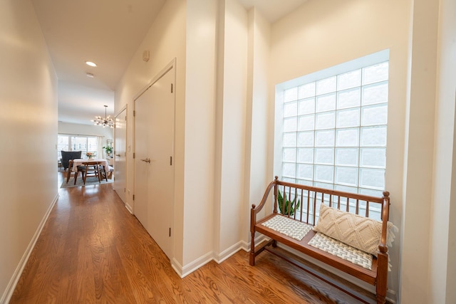 hall with baseboards, recessed lighting, an inviting chandelier, and wood finished floors