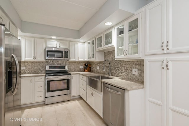 kitchen with light tile patterned floors, sink, white cabinetry, stainless steel appliances, and tasteful backsplash