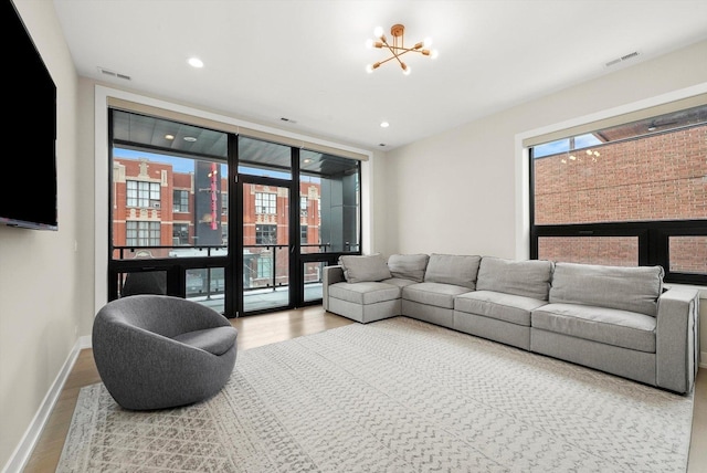 living area featuring a wall of windows, visible vents, baseboards, and wood finished floors