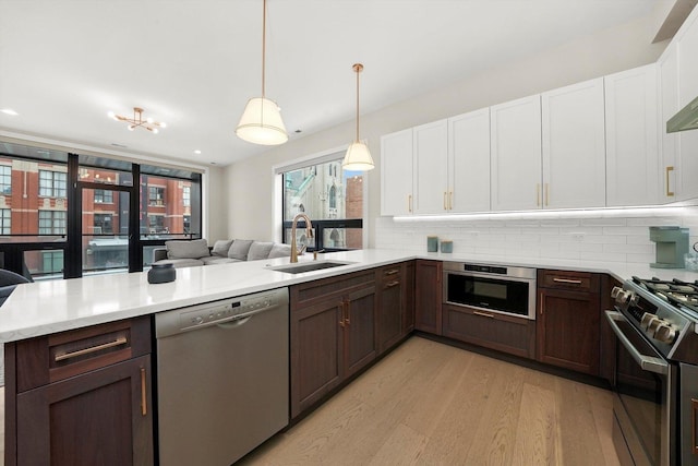 kitchen featuring decorative backsplash, appliances with stainless steel finishes, open floor plan, a sink, and dark brown cabinets