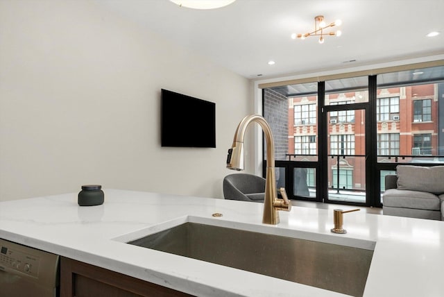 kitchen with light stone counters, open floor plan, a sink, and dishwashing machine