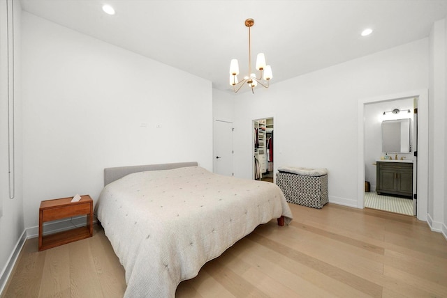 bedroom with a walk in closet, recessed lighting, a chandelier, light wood-type flooring, and baseboards