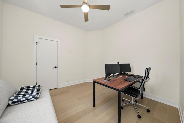 office with a ceiling fan, visible vents, light wood-style flooring, and baseboards