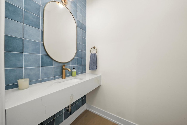 bathroom featuring a sink, tile walls, baseboards, and wood finished floors