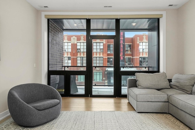 interior space with a wall of windows, visible vents, baseboards, and wood finished floors