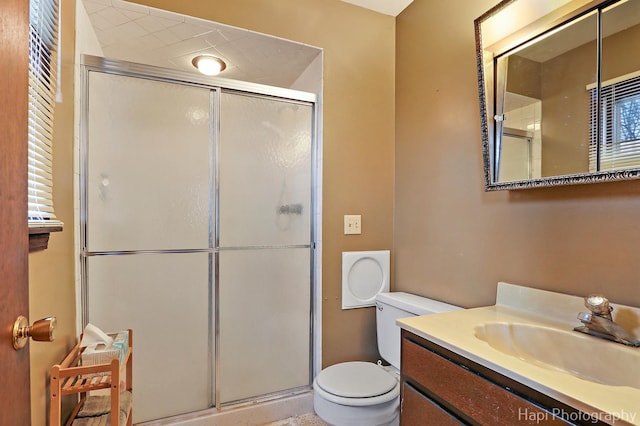 bathroom featuring toilet, an enclosed shower, and vanity