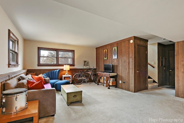 carpeted living room featuring wood walls