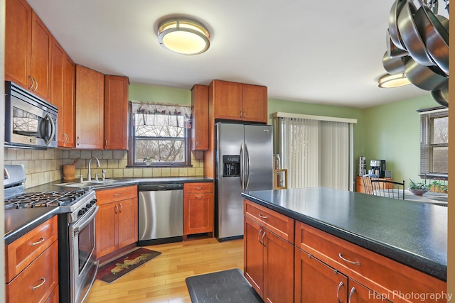 kitchen with light wood-type flooring, appliances with stainless steel finishes, sink, and backsplash