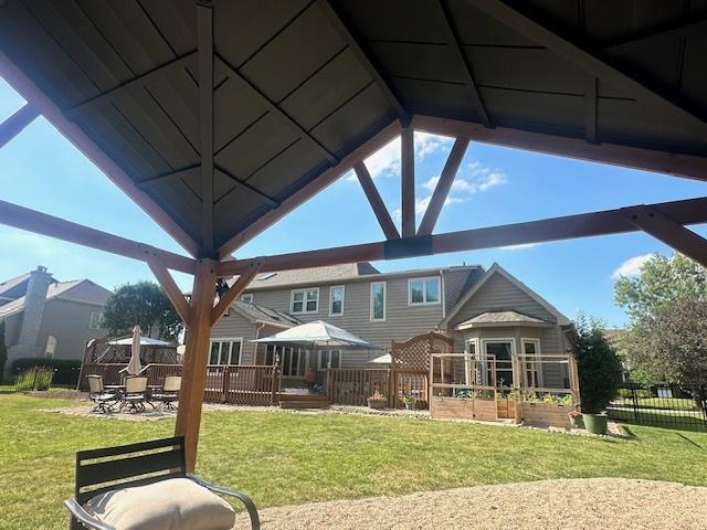 exterior space featuring fence, a deck, a lawn, and a gazebo