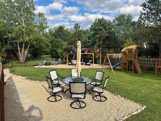 view of patio featuring fence private yard, outdoor dining area, a playground, and a gazebo