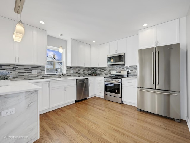 kitchen featuring white cabinetry, appliances with stainless steel finishes, sink, and pendant lighting