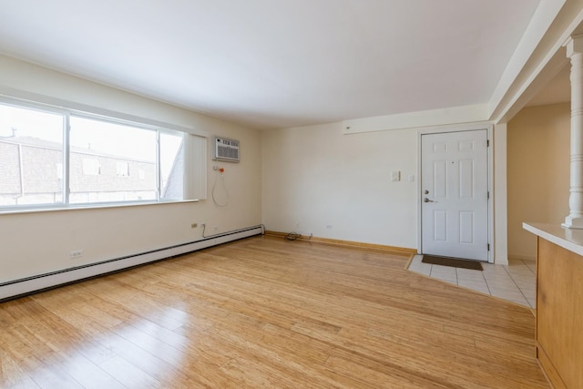 interior space featuring light wood-type flooring, ornate columns, a baseboard radiator, and a wall mounted air conditioner