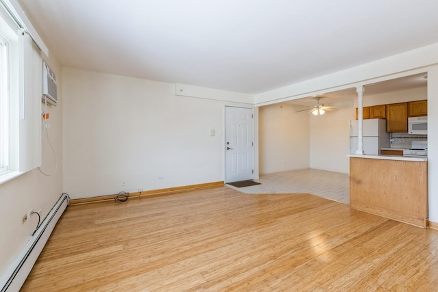 unfurnished living room with ceiling fan, light wood-type flooring, a wall mounted AC, and a baseboard heating unit