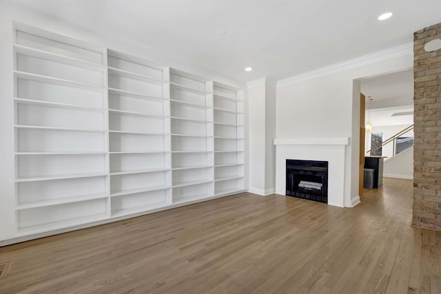 unfurnished living room with recessed lighting, a fireplace, wood finished floors, baseboards, and crown molding