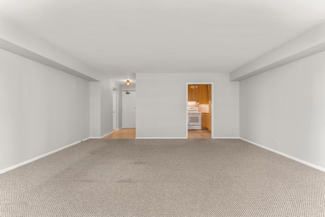 spare room featuring light carpet and baseboards