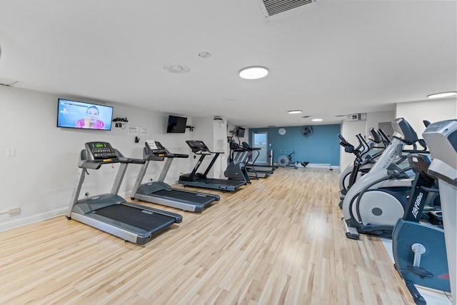 workout area with wood finished floors, visible vents, and baseboards