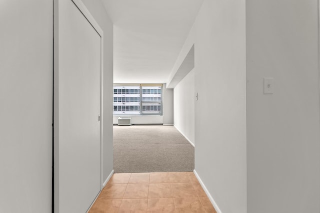 hall with light colored carpet, light tile patterned flooring, and baseboards