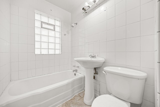 bathroom featuring tile patterned floors, toilet, tile walls, and tiled shower / bath