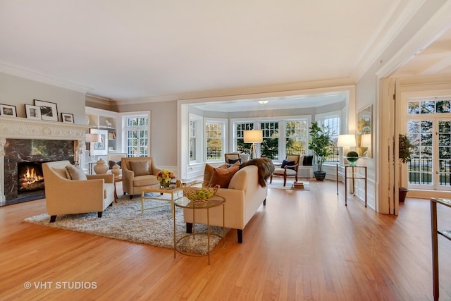 living room with ornamental molding, a premium fireplace, and light wood-type flooring