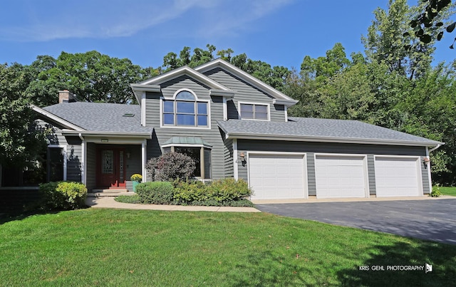 traditional-style home with an attached garage, roof with shingles, driveway, and a front lawn