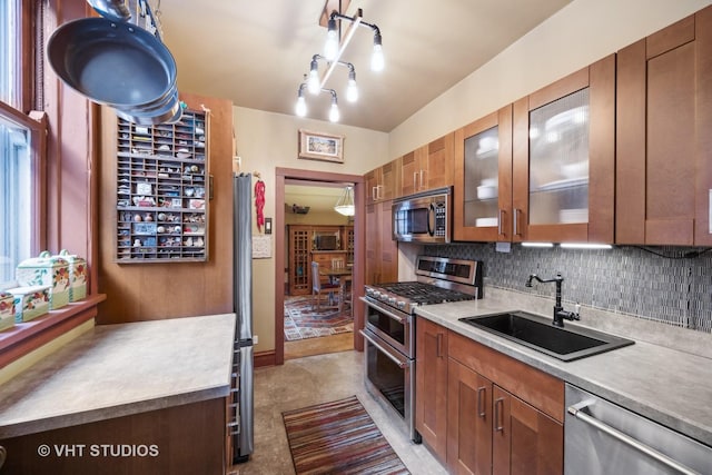 kitchen featuring appliances with stainless steel finishes, brown cabinets, light countertops, and a sink