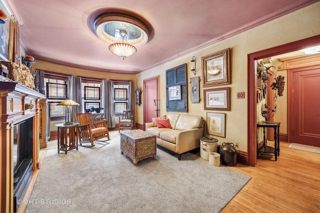 sitting room featuring light wood-style flooring, ornamental molding, baseboards, and a glass covered fireplace