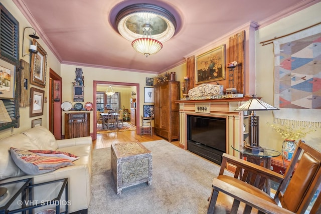 living area featuring ornamental molding, a glass covered fireplace, and light wood-style floors