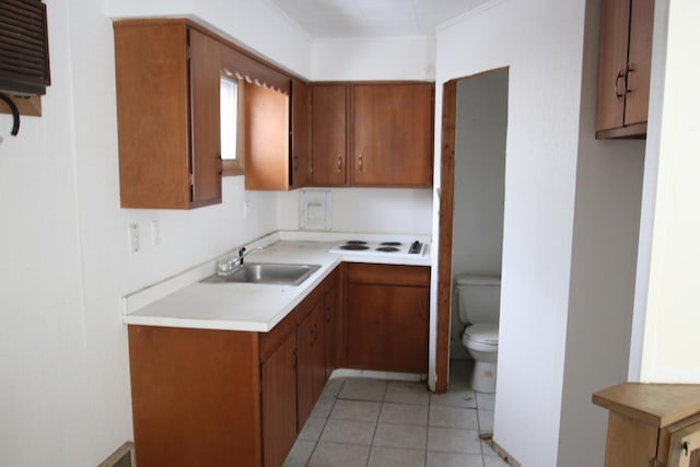 kitchen featuring brown cabinets, light tile patterned floors, light countertops, and a sink