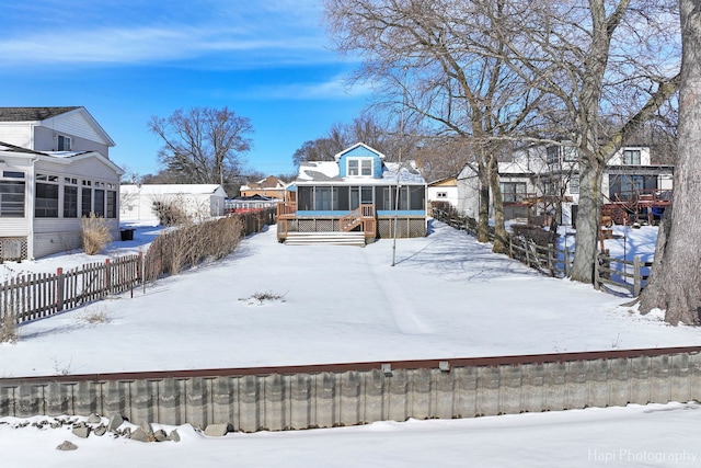 yard covered in snow with a residential view, fence, and a sunroom