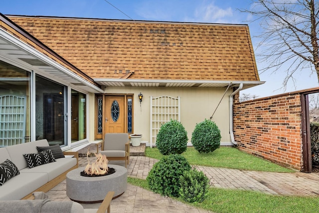 rear view of house featuring a shingled roof, a patio area, an outdoor living space with a fire pit, and stucco siding