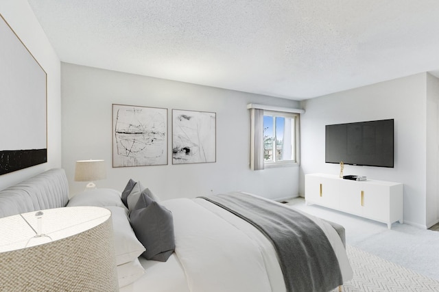 bedroom featuring light carpet, baseboards, and a textured ceiling