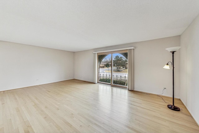 spare room featuring a textured ceiling and light wood-style floors